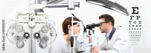optometrist doing eyesight with woman patient measurement with slit lamp on white background photo