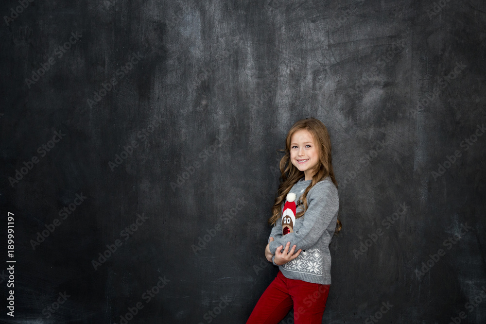 Pretty girl stands on the black background of a chalkboard and smile Pretty girl stands on the black background of a chalkboard and smile