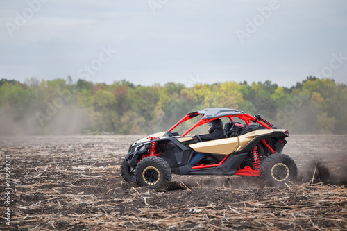 Red quad bike with a driver in plowed field