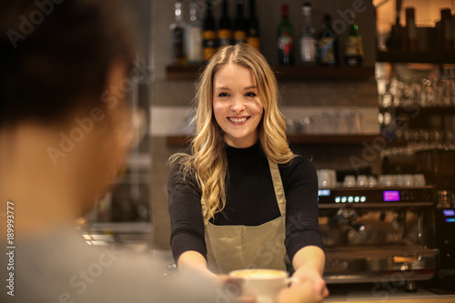 Smiling waitress serving a hot drink photo
