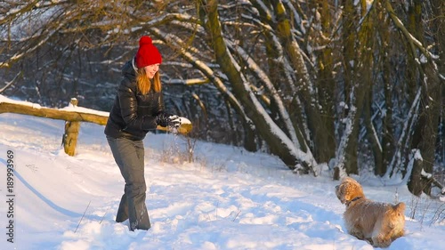 Girl in red hat playing with dog in winter forest. photo
