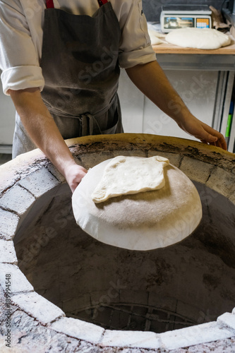 Chef making khachapuri in tandoor. Traditional Georgian starchy food meal photo