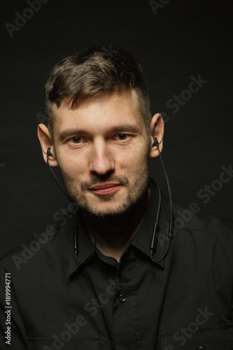 Man in headphones and black shirt on a black background