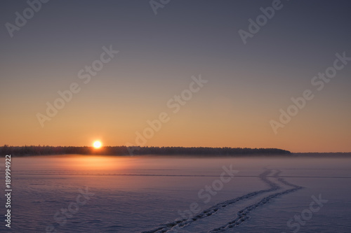 Sunset on a frozen forest lake.