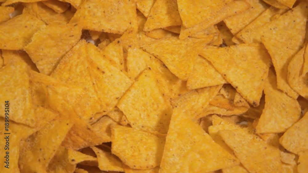 A bunch of tasty nachos rotating over a yellow background. Above close-up shot.
A bunch of tasty nachos rotating over a yellow background. Above close-up shot.