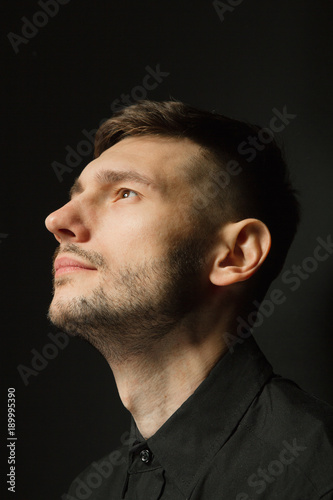Handsome and positive guy in a black shirt on a black background