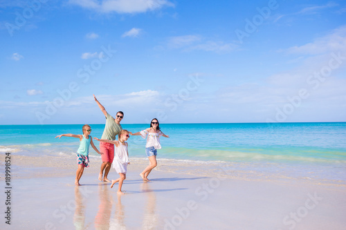 Family of four on beach vacation running and having fun