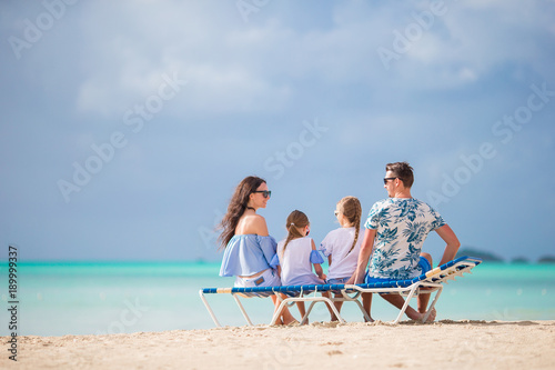 Young family on vacation. Parents and kids on sunbed enjoy the sea view