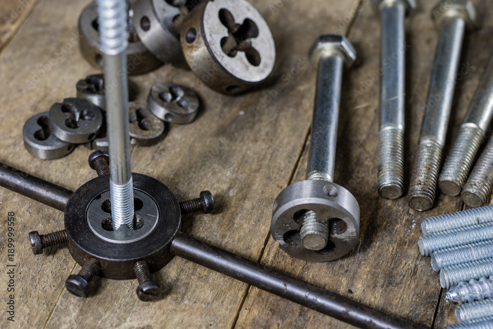 Fototapeta premium Metalwork tools on the workshop table. Threading dies and taps in an old dusty workshop.