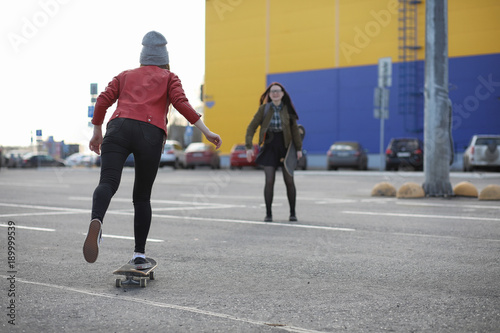 A young hipster girl is riding a skateboard. Girls girlfriends f