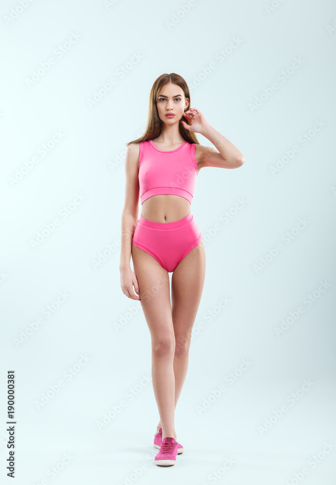 Full length portrait of young beautiful girl in pink sportswear and sneakers posing in studio Full length portrait of young beautiful girl in pink sportswear and sneakers posing in studio