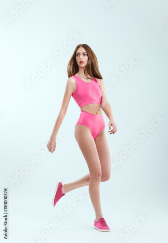 Full length portrait of young beautiful girl in pink swimsuit in motion
