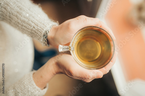 female hands holding a mug of hot tea