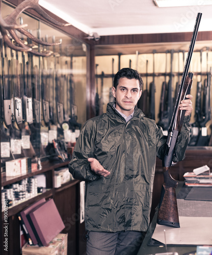 Man choosing rifle in shop photo