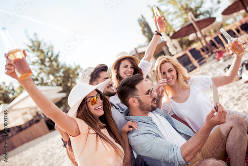 Friends taking selfie with smart phone on the beach.