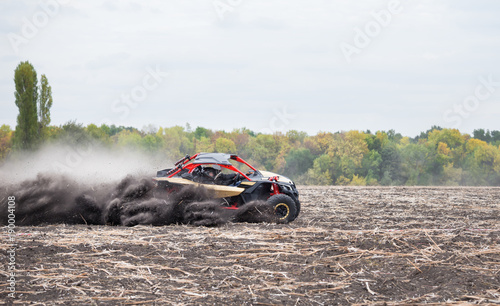 Quad bike quickly rides in the dust clubs across the field