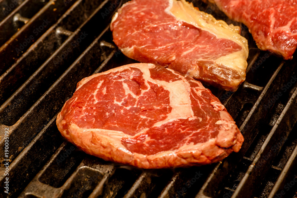 The chef cooks steaks on the grill.