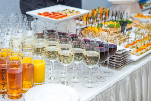 Catering table with alcoholic and non-alcoholic drinks, dishes and snacks food on the event. Service at business meeting, party, weddings. Selective focus, space for text.