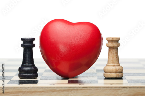 Two chess rooks, black and white, and a red heart between them on the chessboard