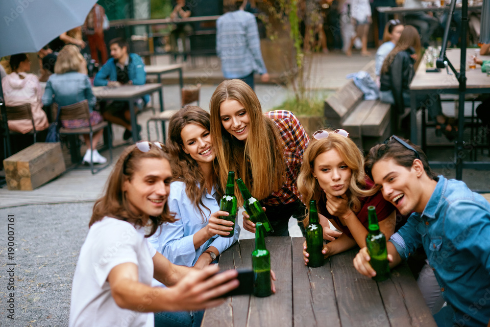 Fototapeta premium Group Of Friends Drinking Beer And Taking Photos On Phone