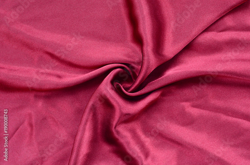 Background texture of cherry red from satin fabric with many folds