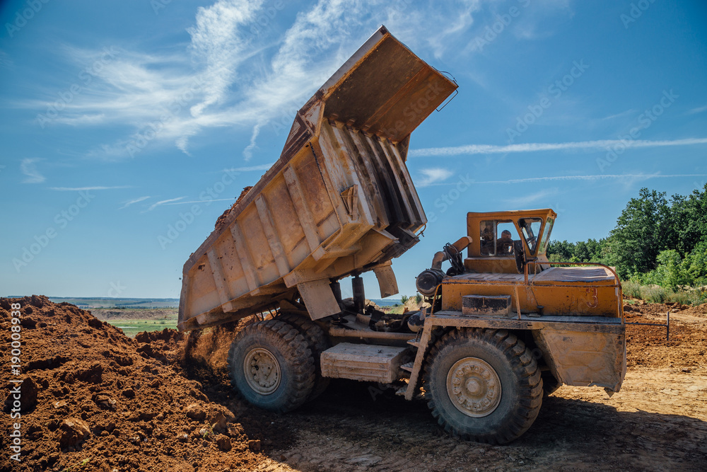 Fototapeta premium Dump truck unloads soil with crashed stone
