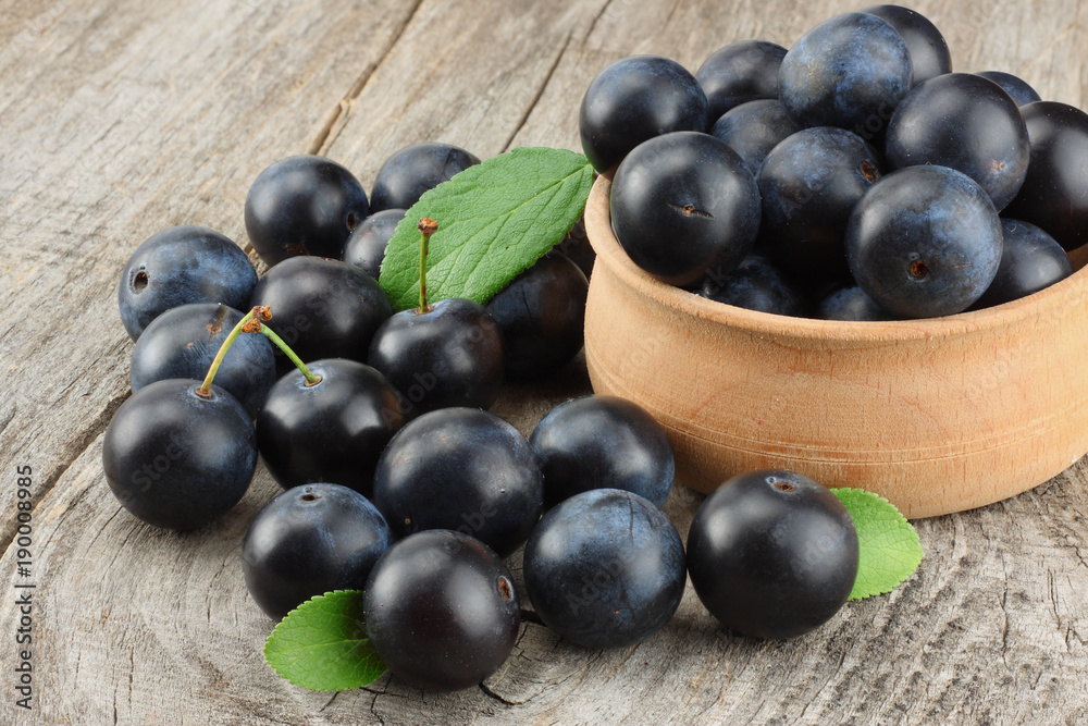blackthorn berries with green leaf on old wooden table blackthorn berries with green leaf on old wooden table