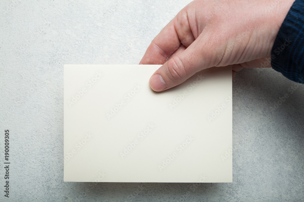 Obraz premium A5 flyer in a male hand on a white vintage background.