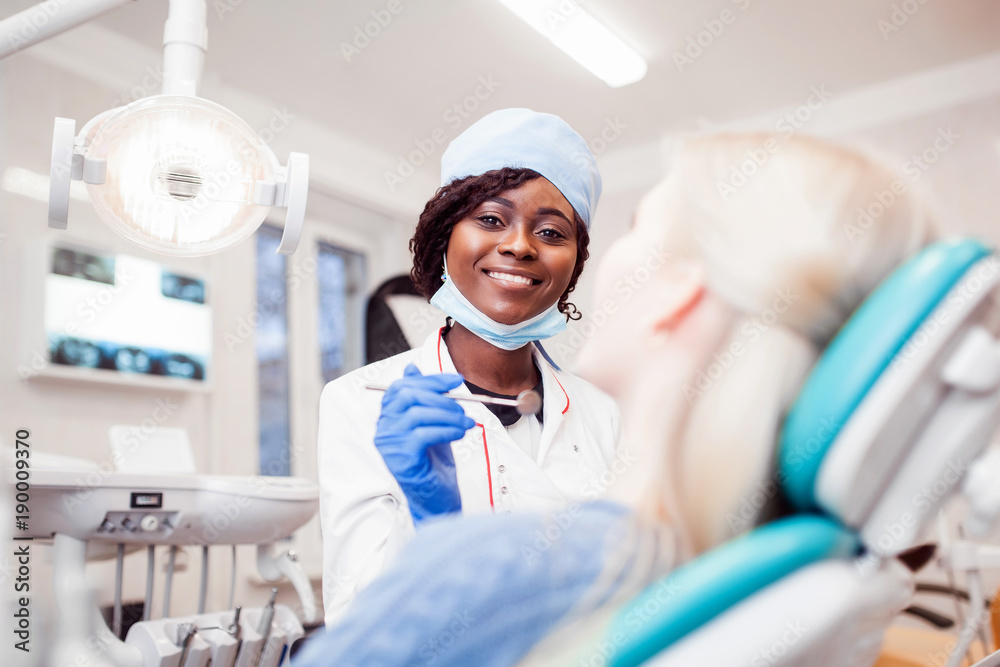 young black girl doctor dentist treats white girl's teeth