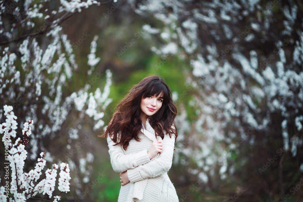 Happy beautiful young woman with long black healthy hair enjoy fresh flowers and sun light in blossom park at sunset. Happy beautiful young woman with long black healthy hair enjoy fresh flowers and sun light in blossom park at sunset.