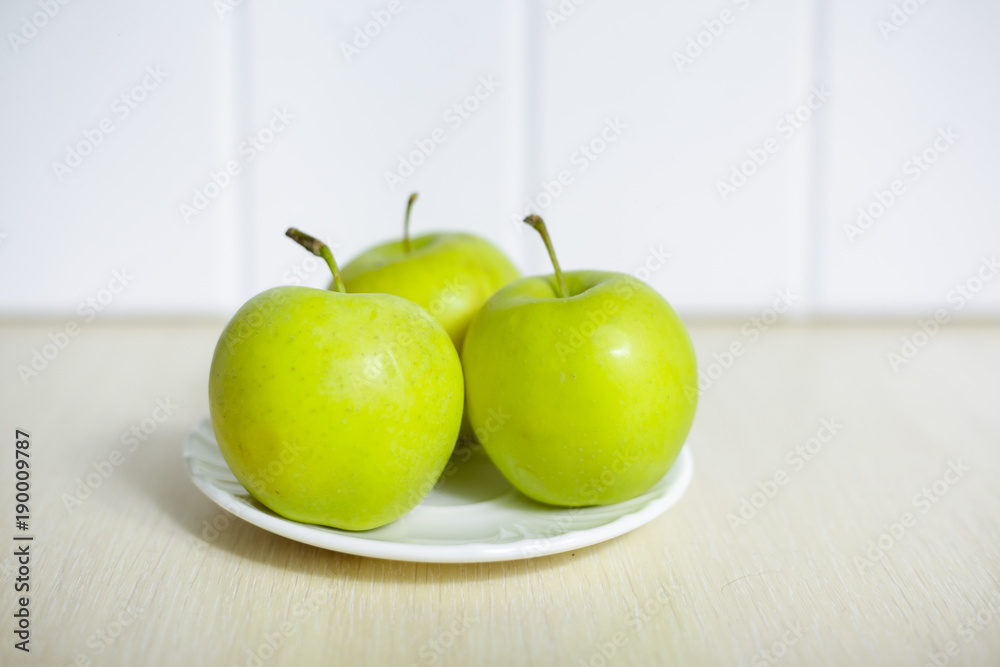 Green apples on a plate on a wooden table. Green apples on a plate on a wooden table.