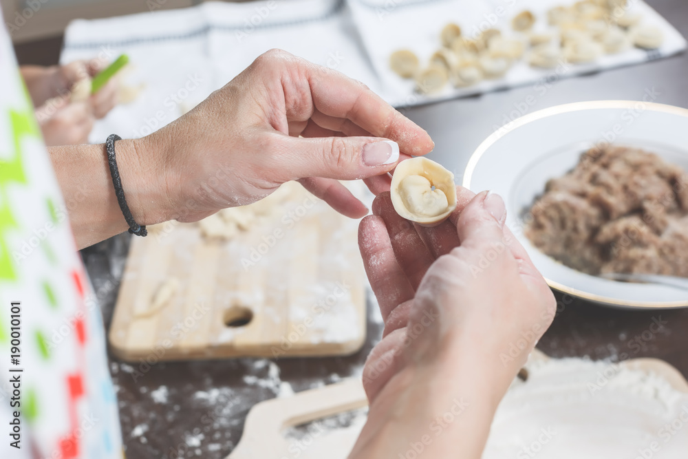 Female hands hold freshly dumplings on the background of kitchen workspace