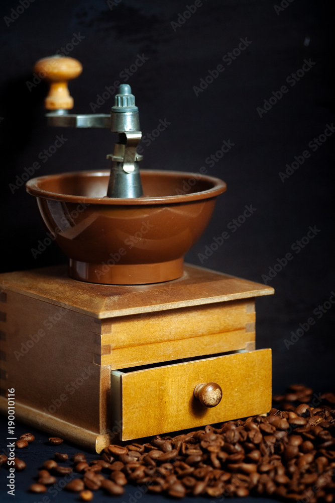Coffee beans and an old hand grinder on a black textured background. Coffee beans and an old hand grinder on a black textured background.