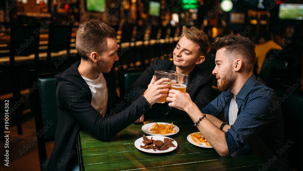 Men raised their glasses with beer in sport pub