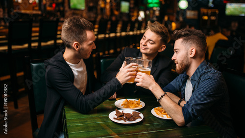 Men raised their glasses with beer in sport pub