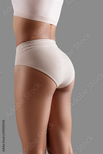 Close up of woman demonstrating fit legs and breech wearing tight underpants. Isolated on background