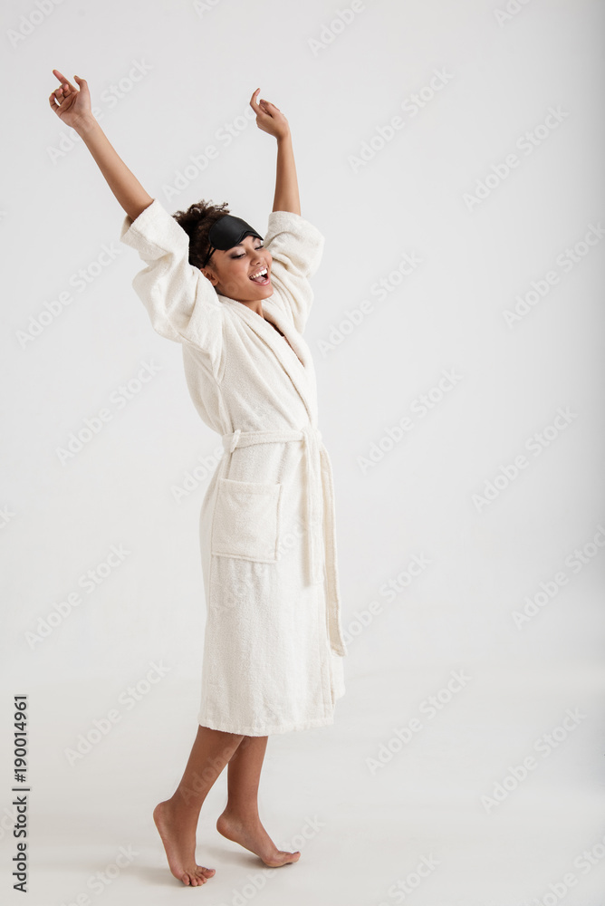 Obraz premium Pleased girl with slim body standing in bathrobe. She is holding her hands up and gaping