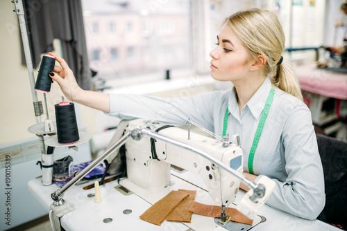 Female dressmaker sews on serger machine