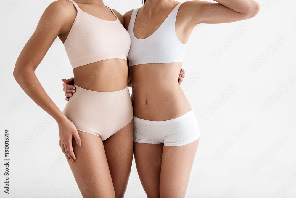 Thin women demonstrating their good looking figures in tight underwear.  Isolated on background Stock Photo