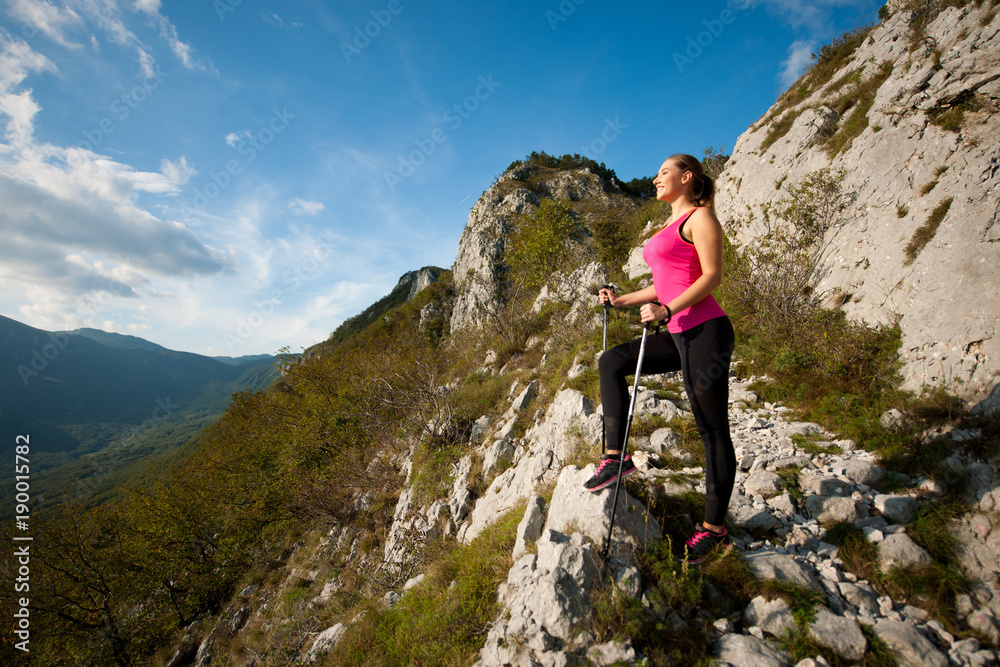 Beautiful young woman hiking in mountains on a sunny summer afternoon