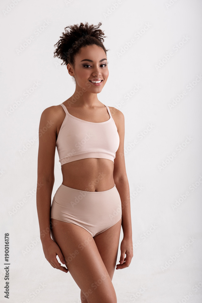 Foto de Beauty concept. Portrait of fit girl in underwear looking at camera  with joy. She is wearing high waist panties and comfortable bra. Isolated  on background do Stock