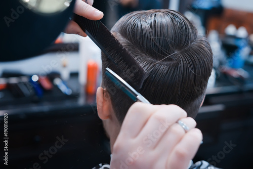 It's time for a new hairdo.The hands of the hairdresser hold a comb and scissors. haircut in the hairdresser's.Master hairdresser performs a man's haircut