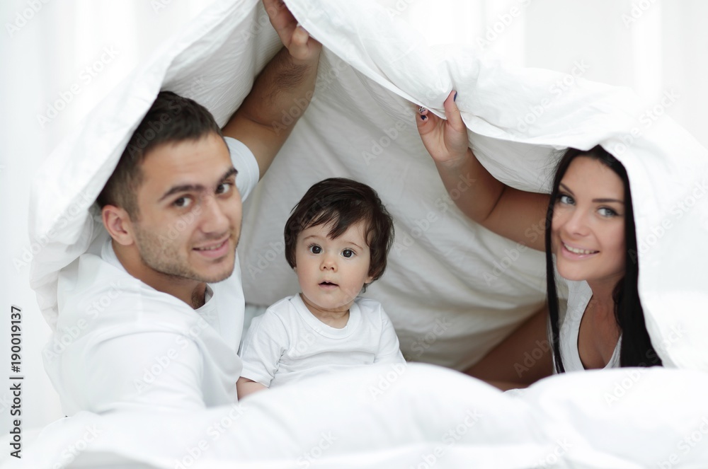 Families with children in bed under a blanket Families with children in bed under a blanket