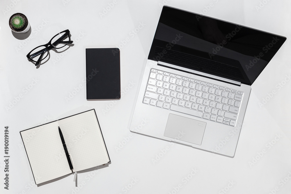 Modern White minimalistic desk table with laptop,, notebook with pen and eyeglasses. Top view with copy space. Working desk table concept. Modern White minimalistic desk table with laptop,, notebook with pen and eyeglasses. Top view with copy space. Working desk table concept.
