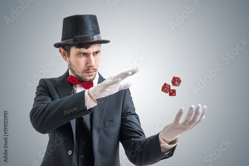 Young illusionist or magician is showing magic trick with levitating dice.