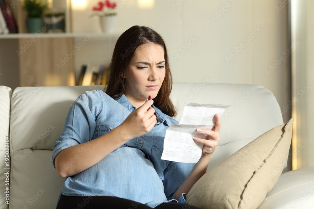 Confused pregnant woman reading a leaflet before take a pill Confused pregnant woman reading a leaflet before take a pill