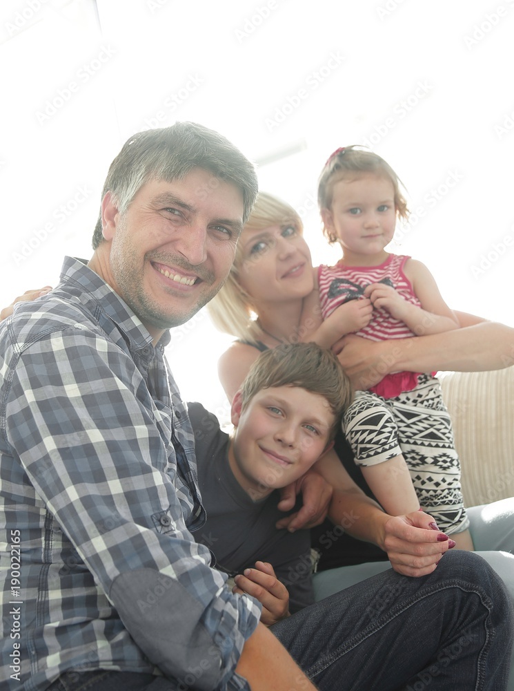 family with two children sitting together and looking at camera