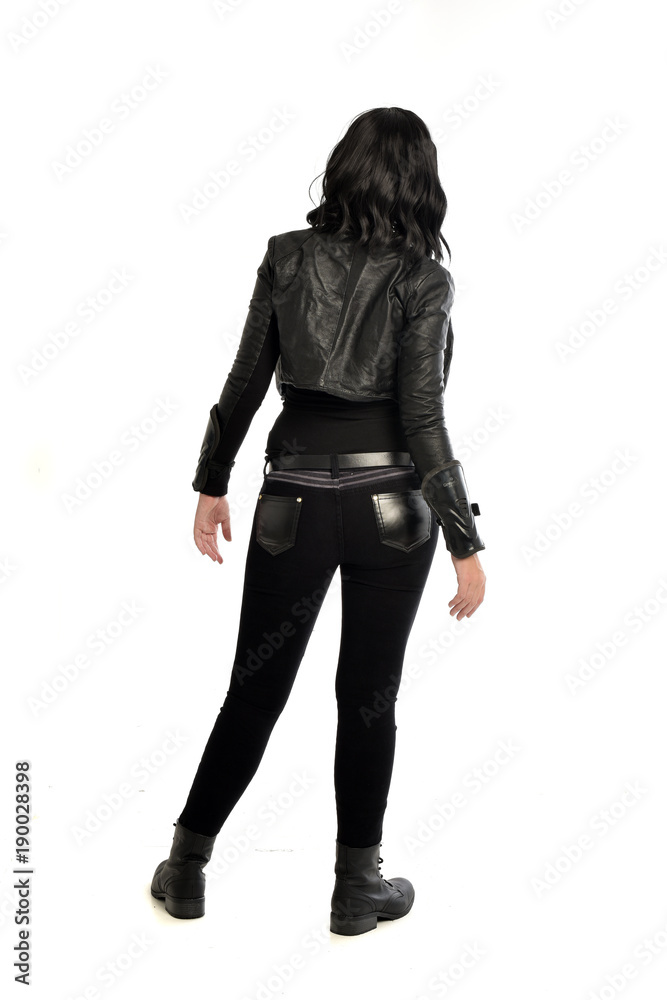full length portrait of black haired girl wearing leather outfit. standing pose view from behind, on a white background full length portrait of black haired girl wearing leather outfit. standing pose view from behind, on a white background