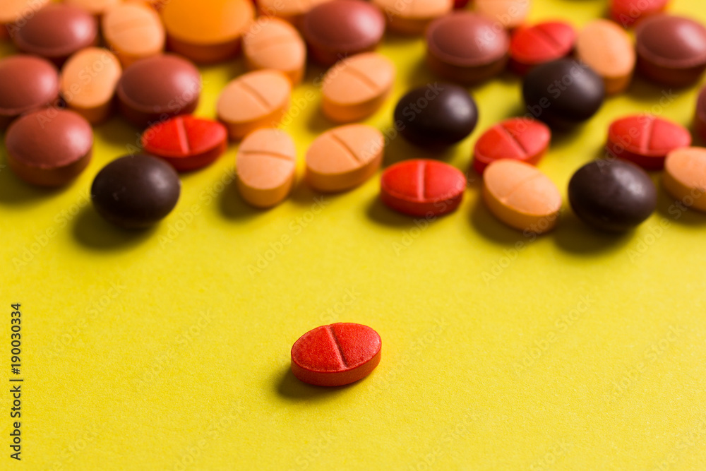 Heap of assorted orange and red capsules on yellow table. Heap of assorted orange and red capsules on yellow table.