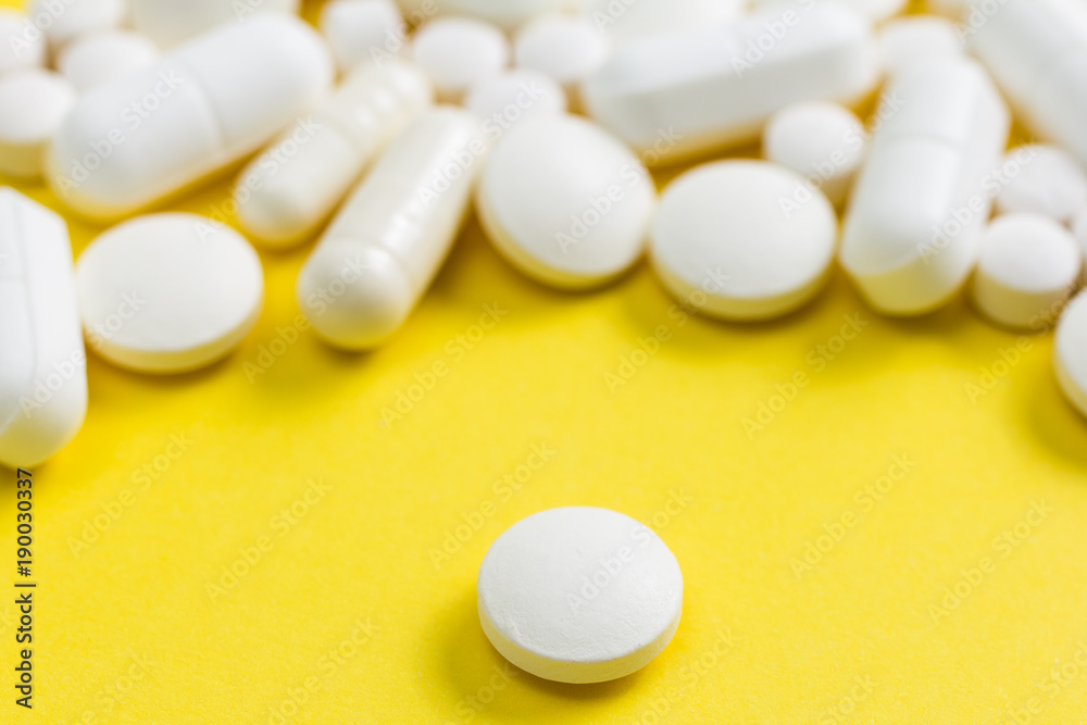 Heap of white capsules on yellow background. Heap of white capsules on yellow background.